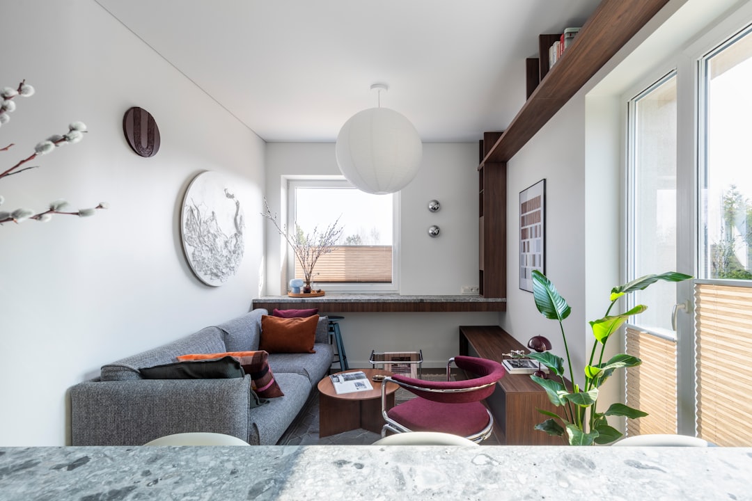 Modern living room with grey sofa, red armchair, and window.